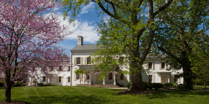 Scenic front landscape photo of the Morven Museum and Garden with blooming trees in front of the building.